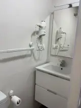 Secador de pelo de pared sobre el lavabo del baño con barra portatoallas y espejo lateral